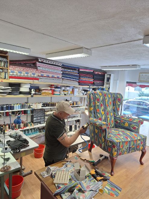Habib klär om en färgstark fåtölj i Tidora Design Ateljé i Göteborg